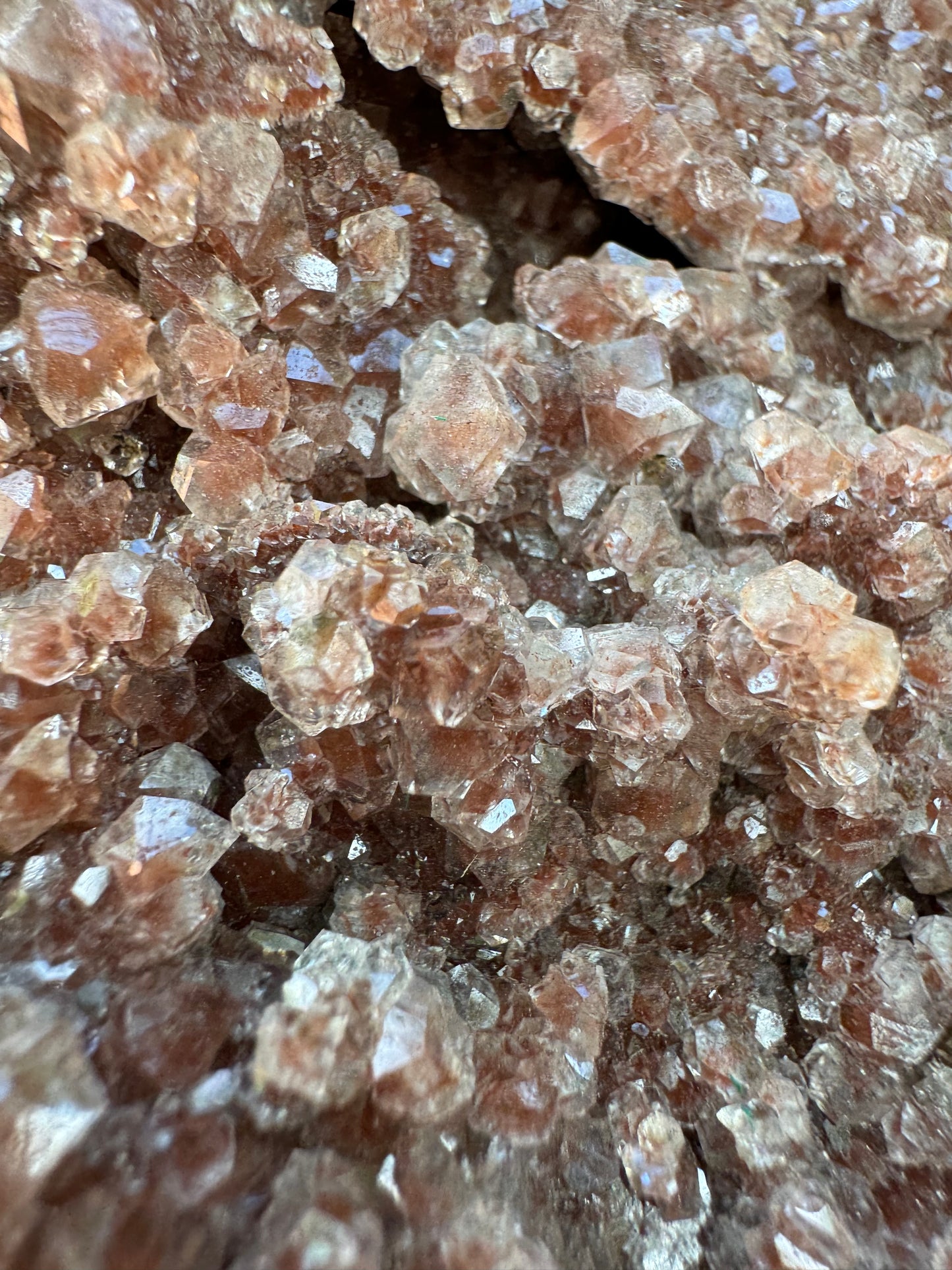 Detail of the calcite druzy showing crystal structure and the peppering of brick-red hematite spotting inside.