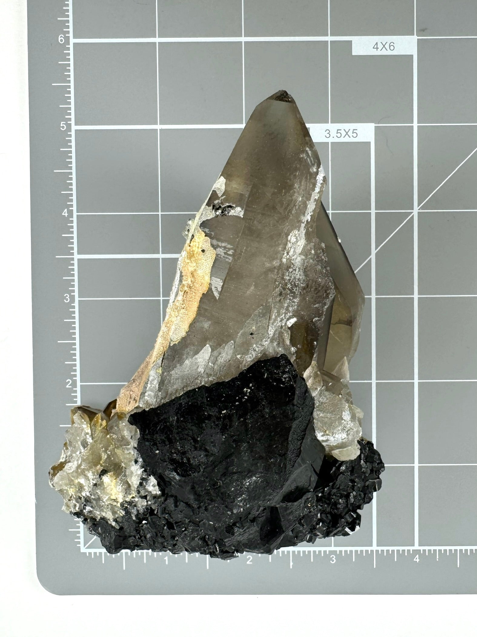 Scale image of the piece at an angle on a measuring mat, with the main point measuring about four inches, and the base a bit over three inches across.