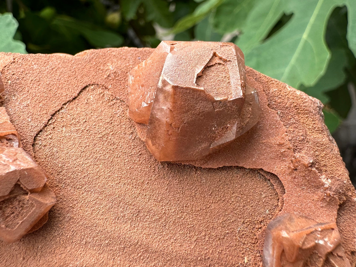 Detail of one of the calcite crystals, showing the sandy texture of the surface is also inside the indented face of the crystal, and appears to be coloring the inside as an inclusion. 