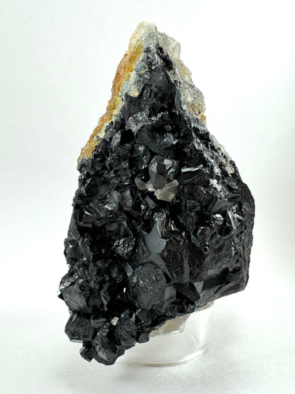 The underside of the specimen, which is composed of semi-irregular growth of schorl crystals. Imprints shaped like inverted bases of prisms, and partial angular lines. Some areas have high luster.