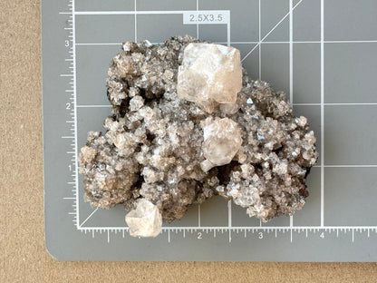 The mineral on a measuring mat, measuring about three and a half by two and half inches.