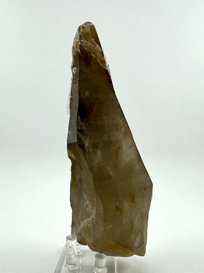 A side-view of the point, a broad triangular face with a long straight edge. The point has good smoky quartz coloration, dark brown at the tip fading to lighter brown at the base, with some darker near-black areas. Interior inclusions are illuminated, showing good clarity though the matte surface obscures it. 