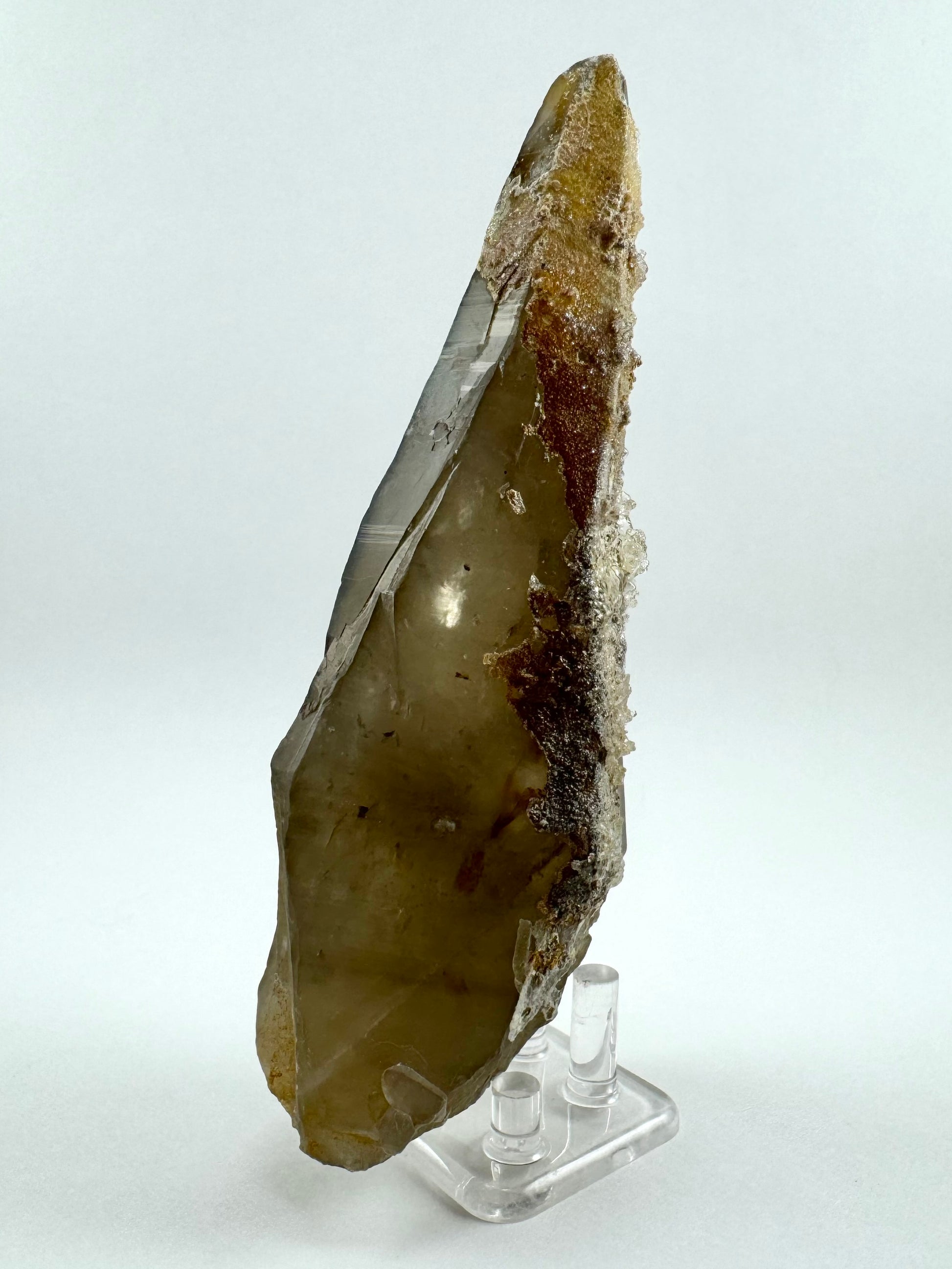 A side-view of the piece showing the hyalite has grown thick with some larger spheres along the right edge. The thin face on the left side has light reflecting off it highlighting complex growth pattern to the face