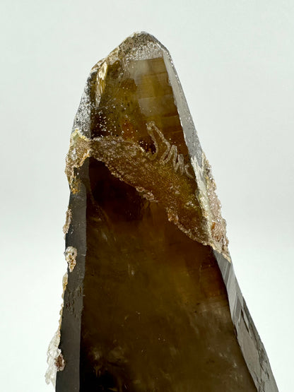 Detail of another side of the tip of the point, with a band of hyalite appearing like small beads forming an irregular shape on the surface of the quartz, with a lighter edge on it. The point has good color.