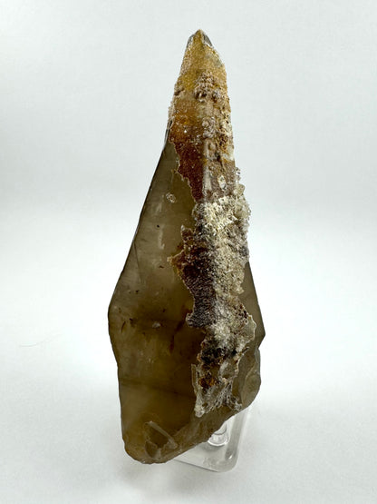 The first of three lighting images: a long tapered smoky quartz point like a spear tip. There is a hyalite crust down one side, tinted by the yellow and red iron staining beneath it.