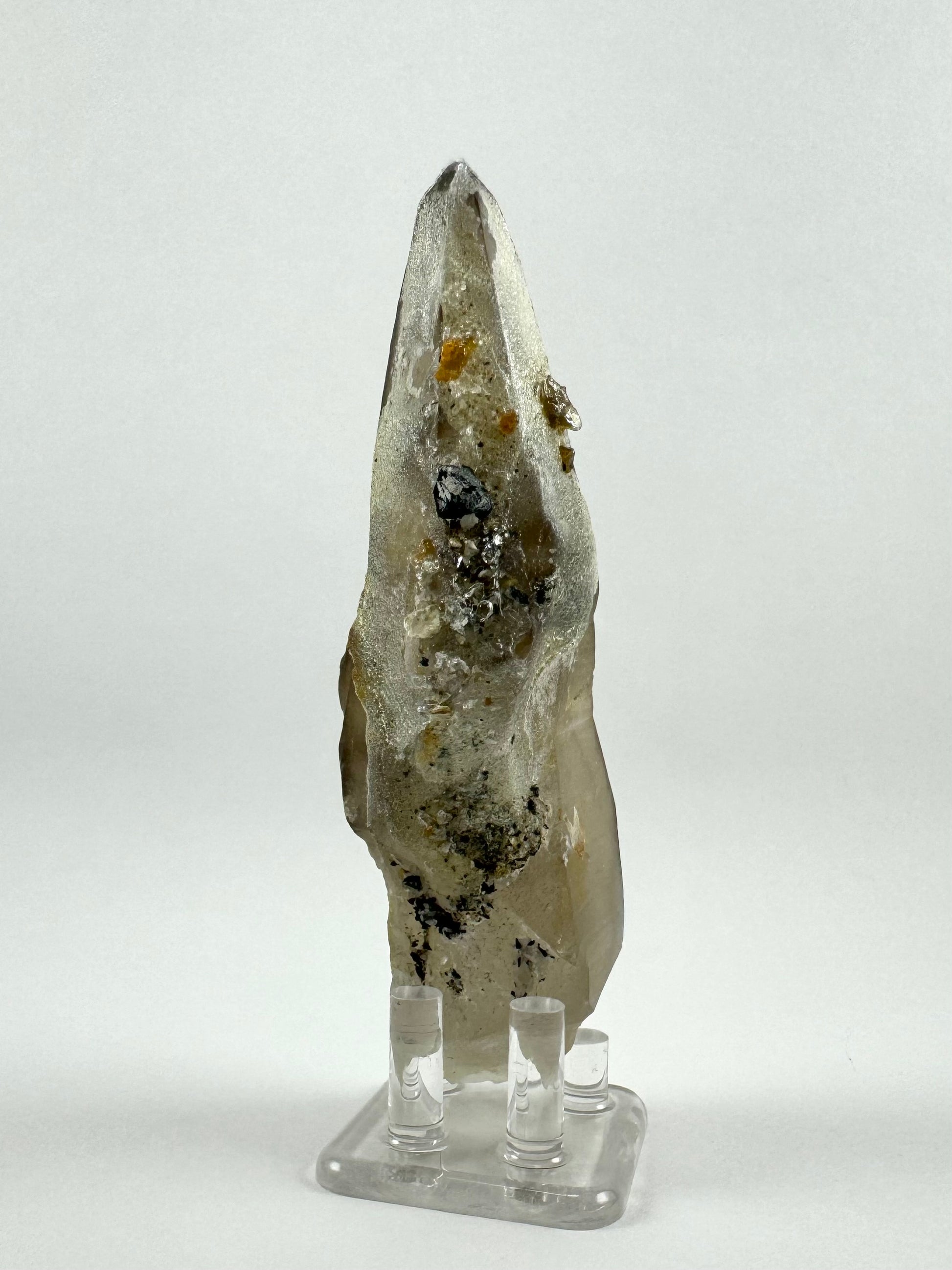 The back side of the piece, which is near-white mostly coated in fine hyalite. There are chunks of black and white minerals entrapped in the hyalite.