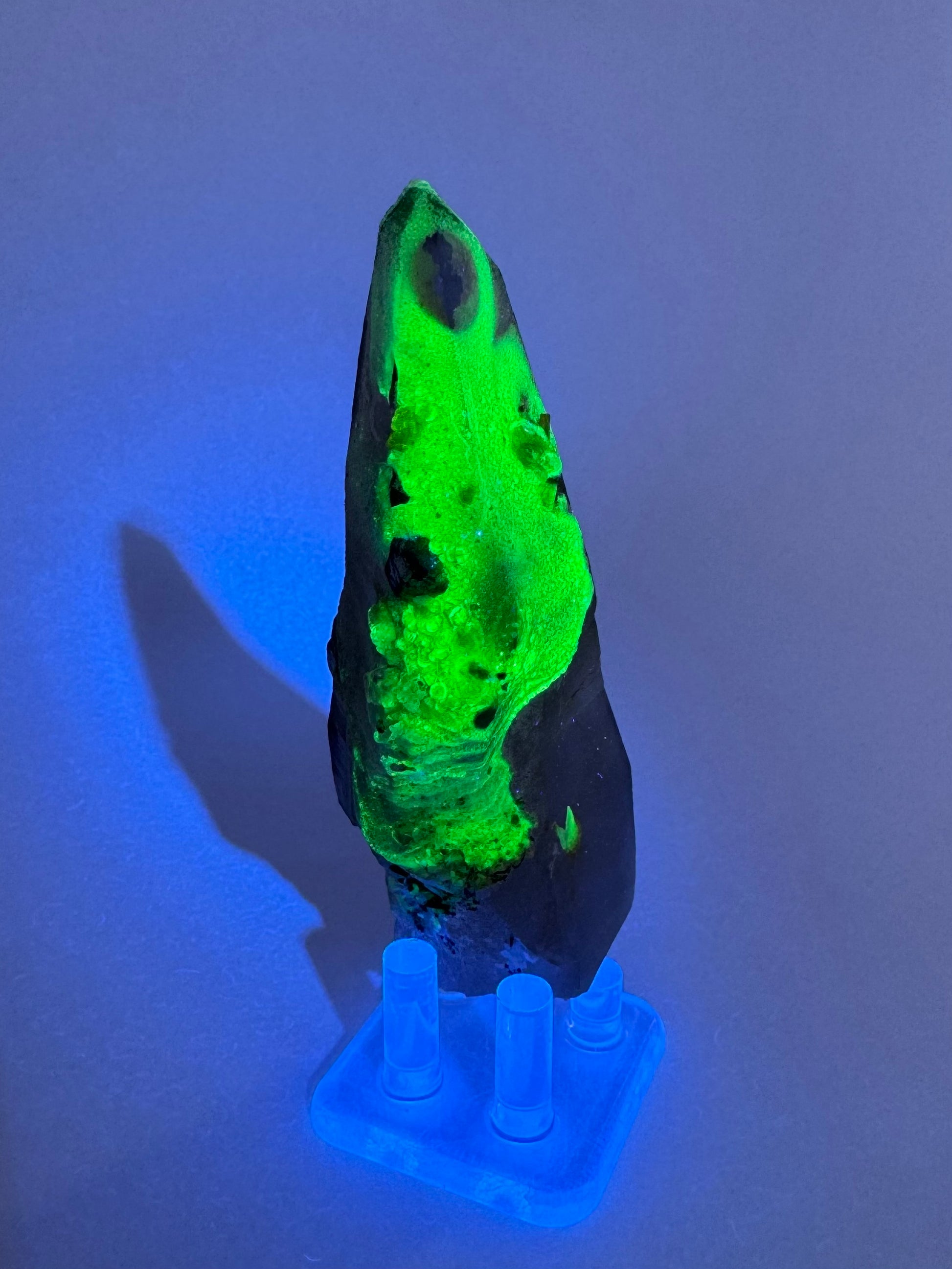 The third of three lighting images: the point in the same position as the previous image in the dark, illuminated in blue-tinted UV light. The hyalite fluoresces strong yellowish-green.