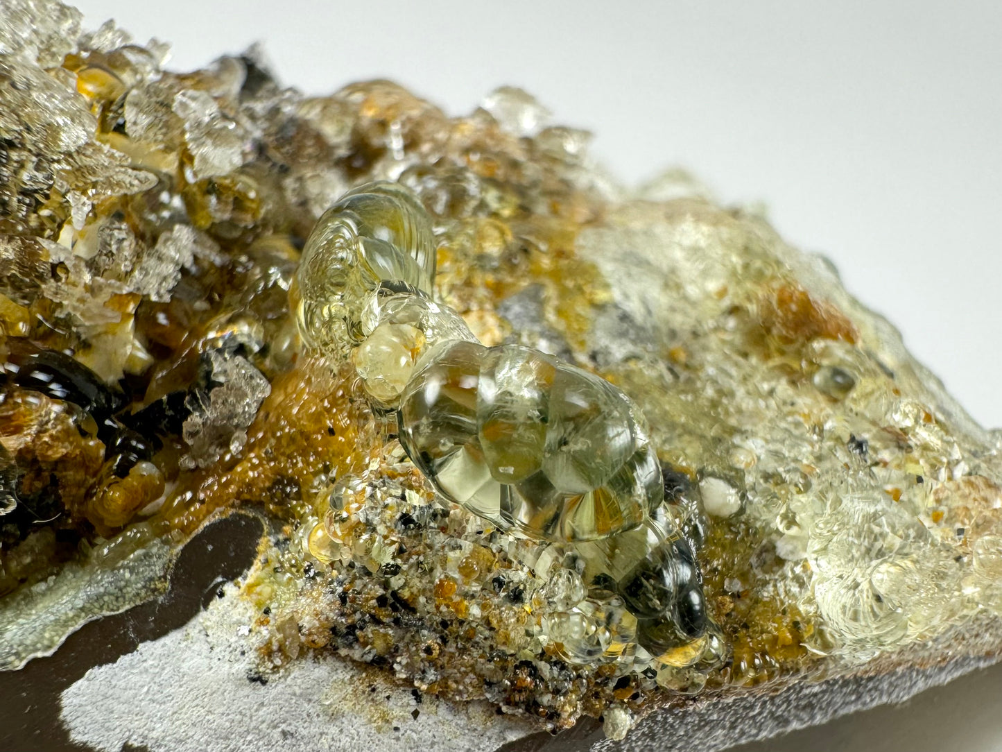 Detail of a cluster of hyalite crystals, extremely clear and shiny bulbous forms with a slight yellow-green tint