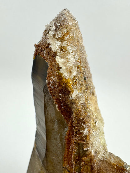 Detail view of the tip of the point, coated in hyalite. The hyalite has formed a shiny beady surface over yellow-brown staining, with a crust of irregular clusters of small needle-like crystals.