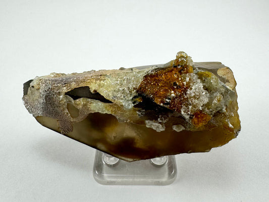 The first of three lighting images: a wide triangular smoky quartz point with a cluster of minerals near the base, coated with a thick hyalite coating.