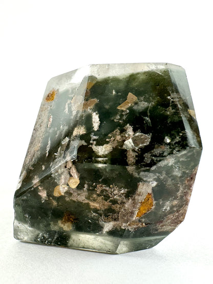 A side view of the specimen in bright white light, showing one of the blade-like inclusions in the green chlorite is shaped like two perfectly symmetrical points of a five-pointed star.