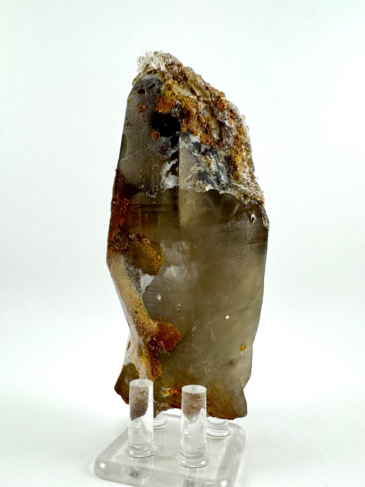 The back of the specimen, covered in a crust on the bottom left and a thick layer of hyalite and other minerals covering the upper right. The crystal is shaped like a flat spearhead.