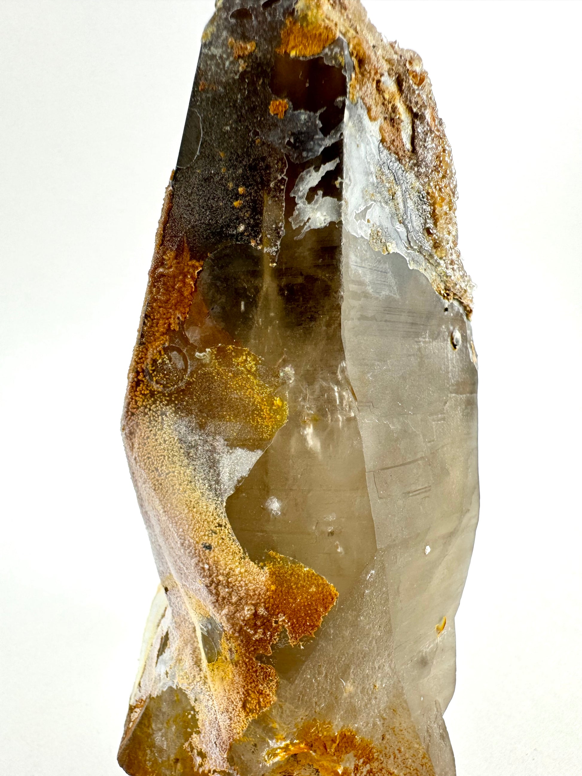 Close view of the irregular crust on the side of the large crystal, with wispy inclusions visible inside and faint horizontal striations.