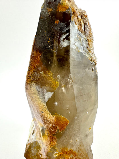 Close view of the irregular crust on the side of the large crystal, with wispy inclusions visible inside and faint horizontal striations.