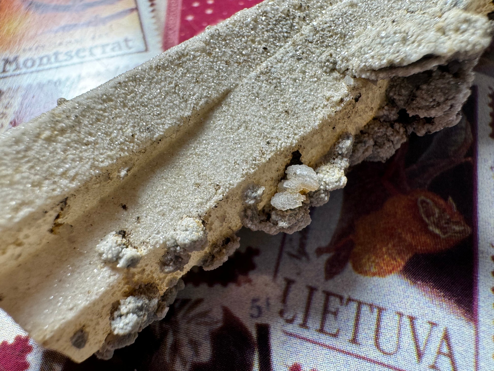 Detail of minerals near the base of the quartz, small clam-shaped calcite crystals bunched together. Viewed closed, the crust on the quartz appears composed of small white bumps in more translucent material.