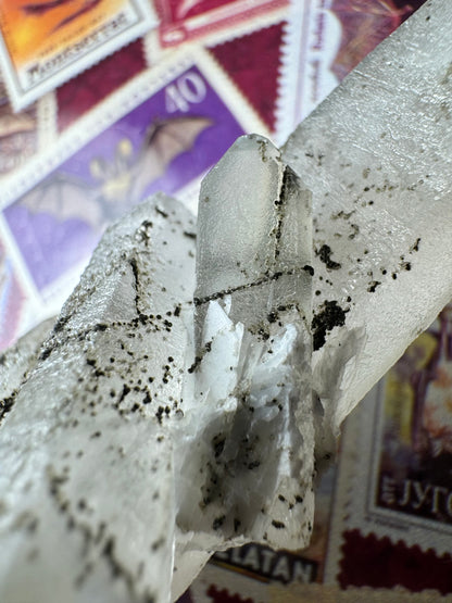 Detail of the small point perched between the larger crystals, showing it has an x of two black lines crossing through it.