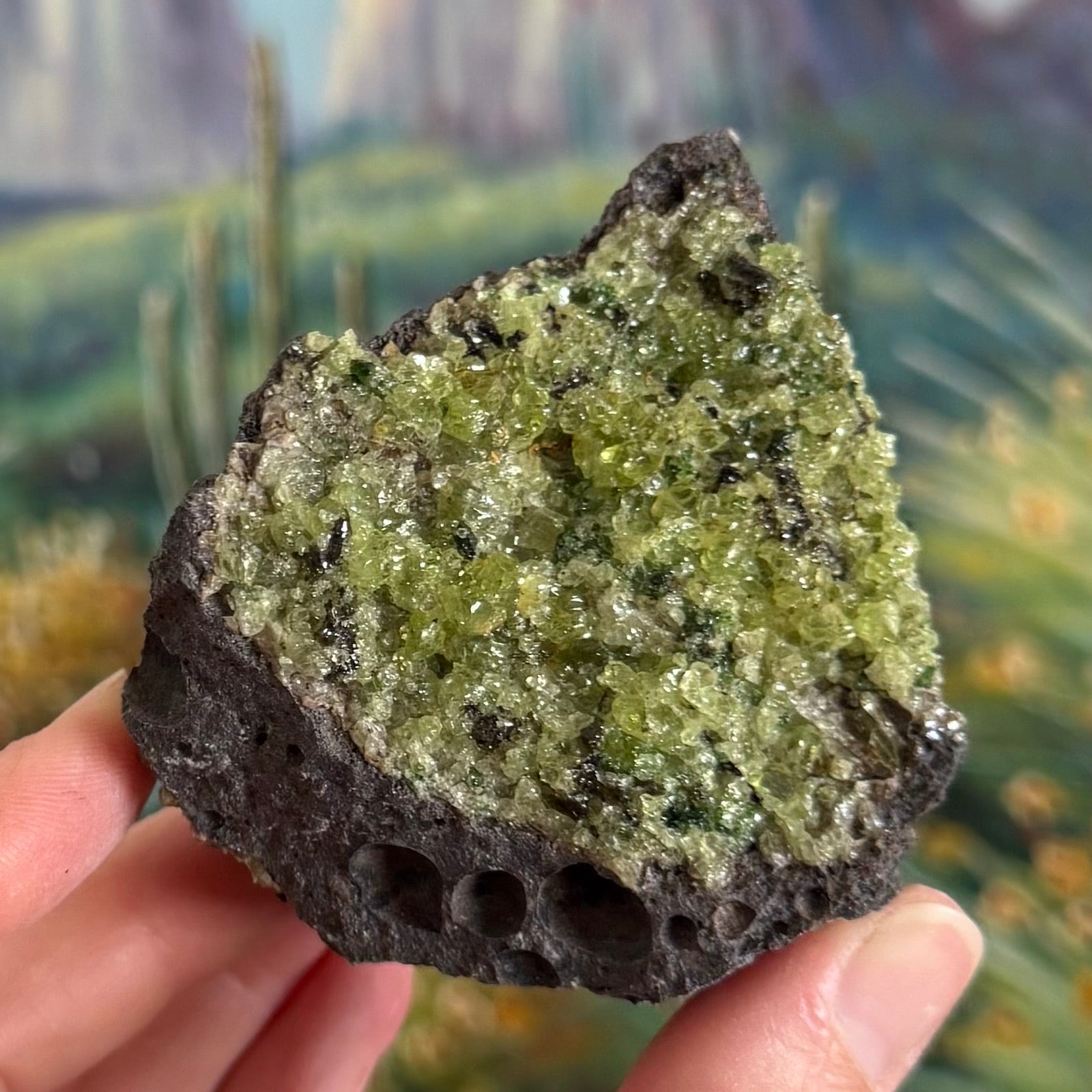 An example piece shown, with a broad face of peridotite on dark gray volcanic rock with a row of large bubble holes along the base. The peridotite is mainly yellow-green with chunky crystals and small vivid green and dark green crystals sprinkled through. The piece corresponds with option E.