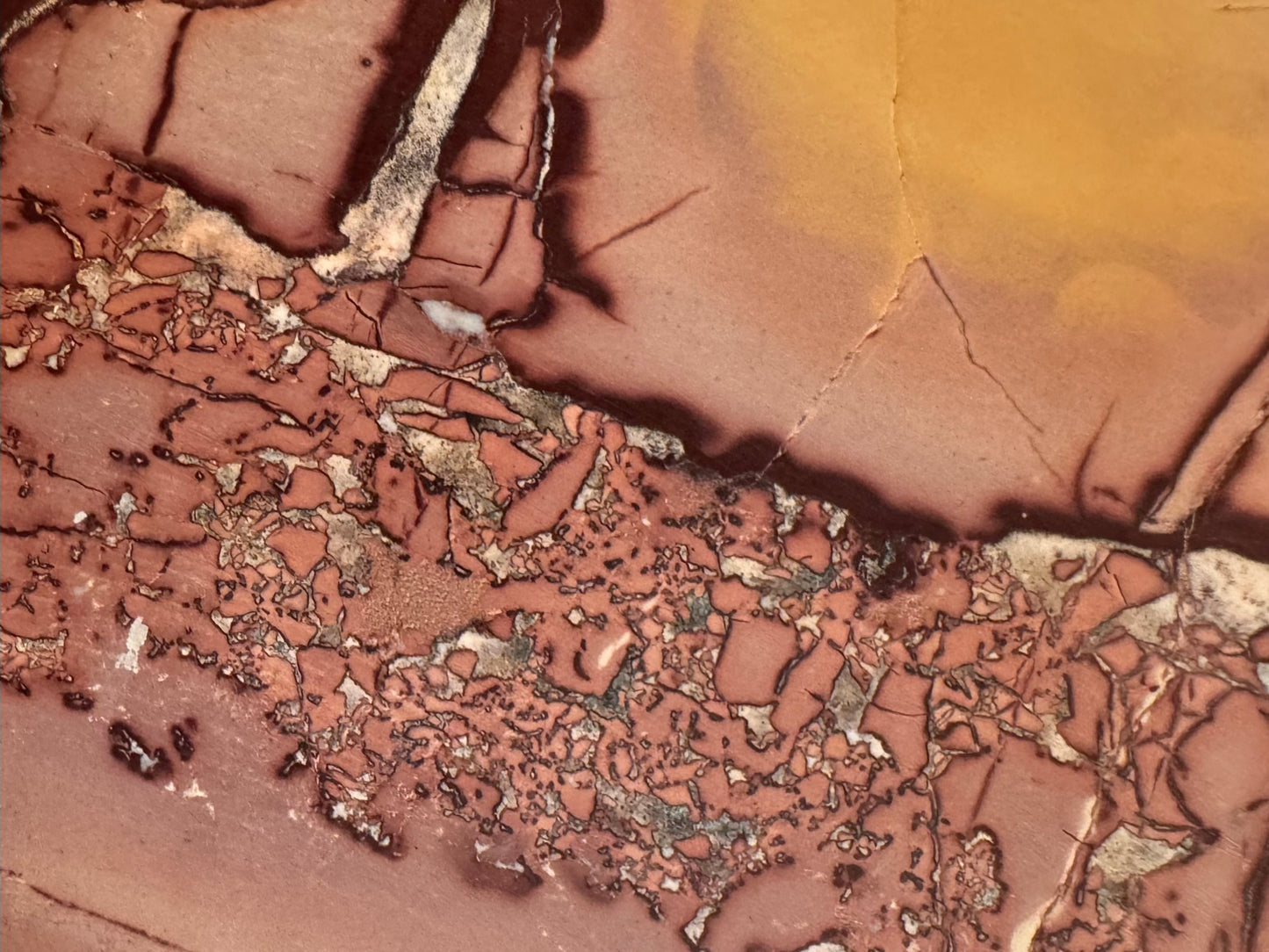 Up close detail of the veining pattern of the jasper, dark red and white on a peach background that fades to yellow