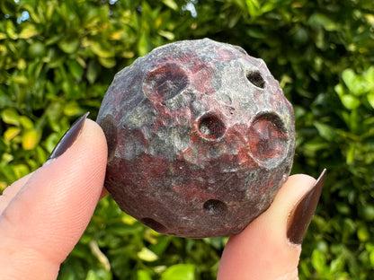 Detail of a moon with dark red splotching on a dark gray background