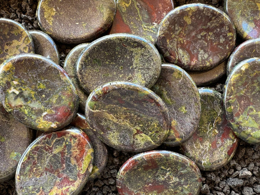 A pile of dragon's blood jasper worry stones. They are mainly dark green in color, with streaks and spots of lime green and red. 