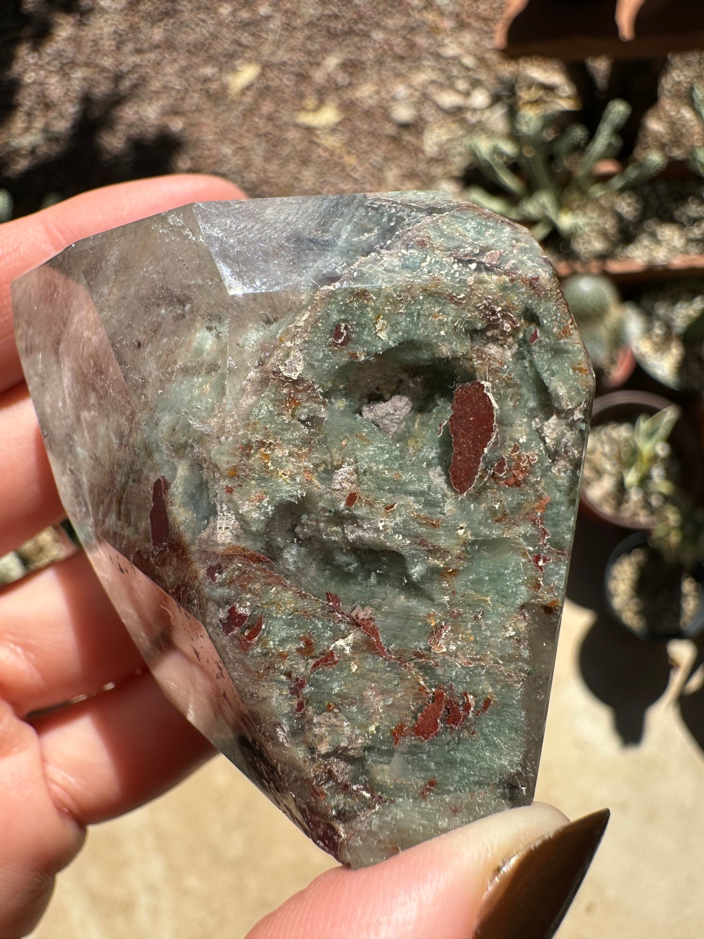 The base of the garden quartz filled with near-opaque mint green and off-white chlorite, with red-brown spots through it.