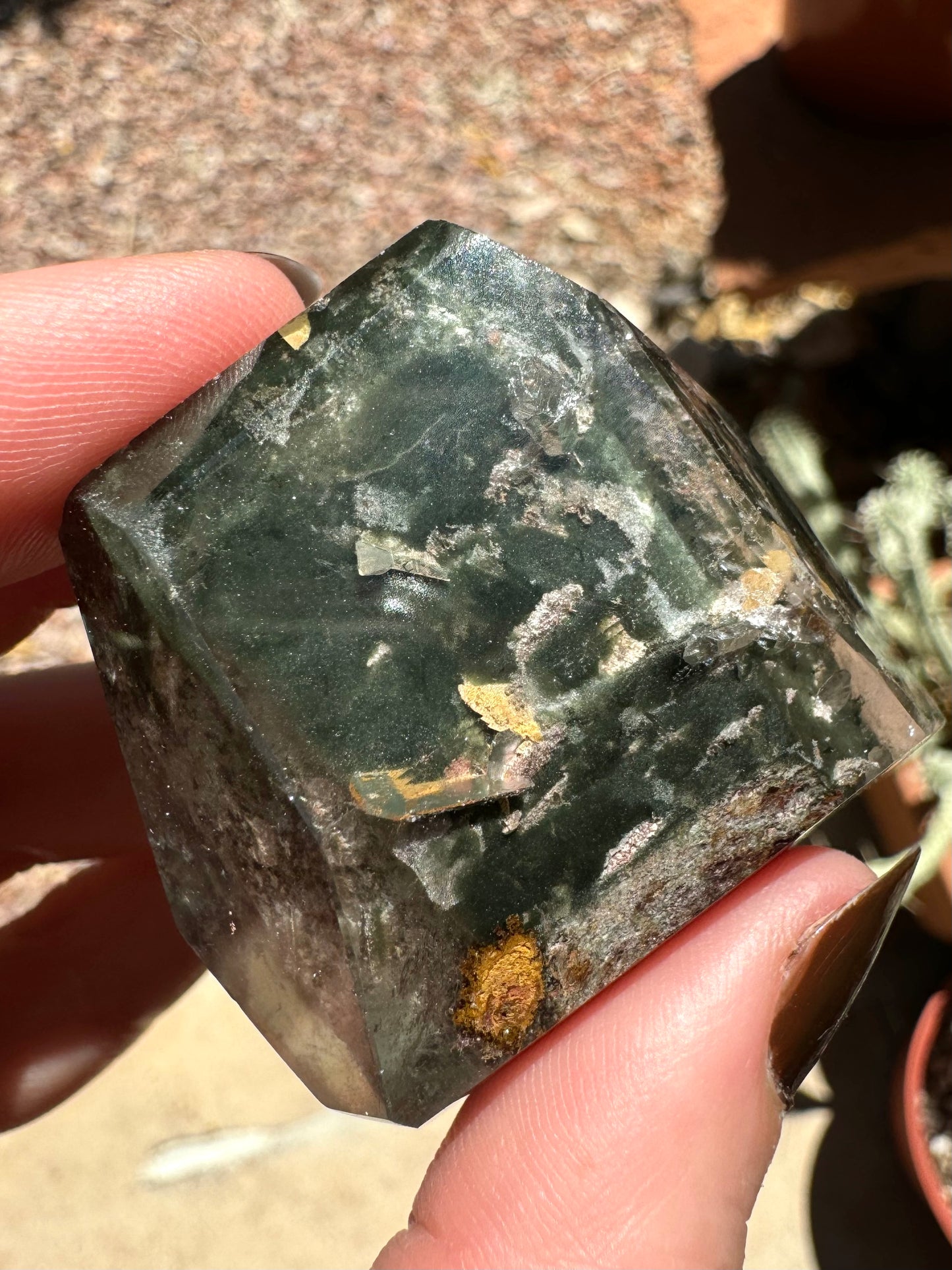 A side of the piece with swirling green chlorite and golden yellow blade-like inclusions