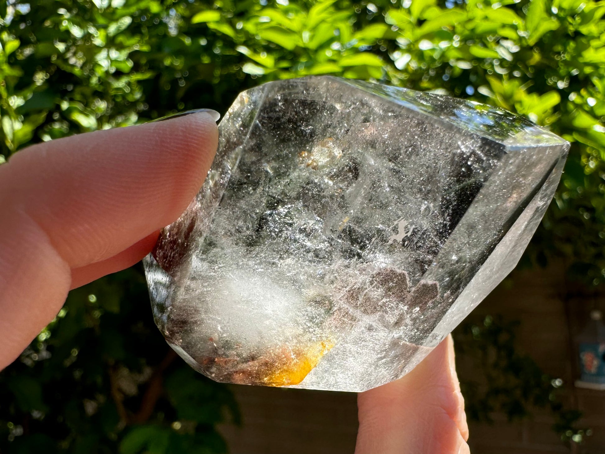 A side of the specimen filled with wispy colorless inclusions bright white in the sunlight, with a bright stripe of 
orange iron staining at the bottom.