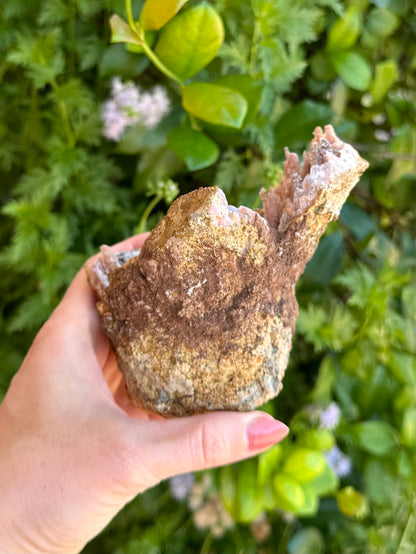 A side of the specimen, with the right-hand side tall. The outside of the geode is a rough brown rock, with a stripe of darker brown dirt across it hiding a repair