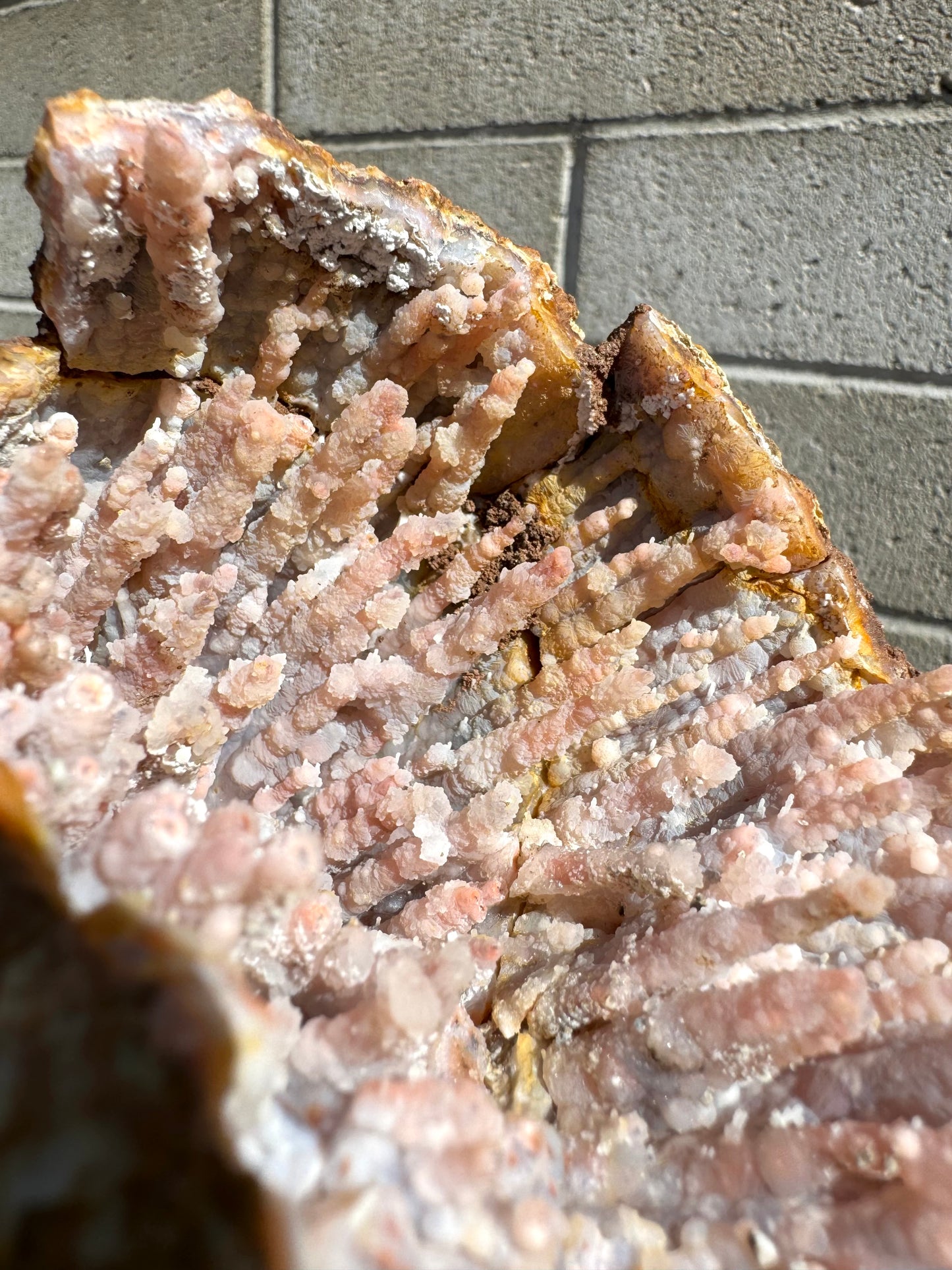 Detail of the juncture between four broken pieces of the geode, showing they were not evenly set during repairs and some white glue is visible, as well as a dark brown dirt-like material that has been used to cover it. The cracks are highlighted by iron staining.