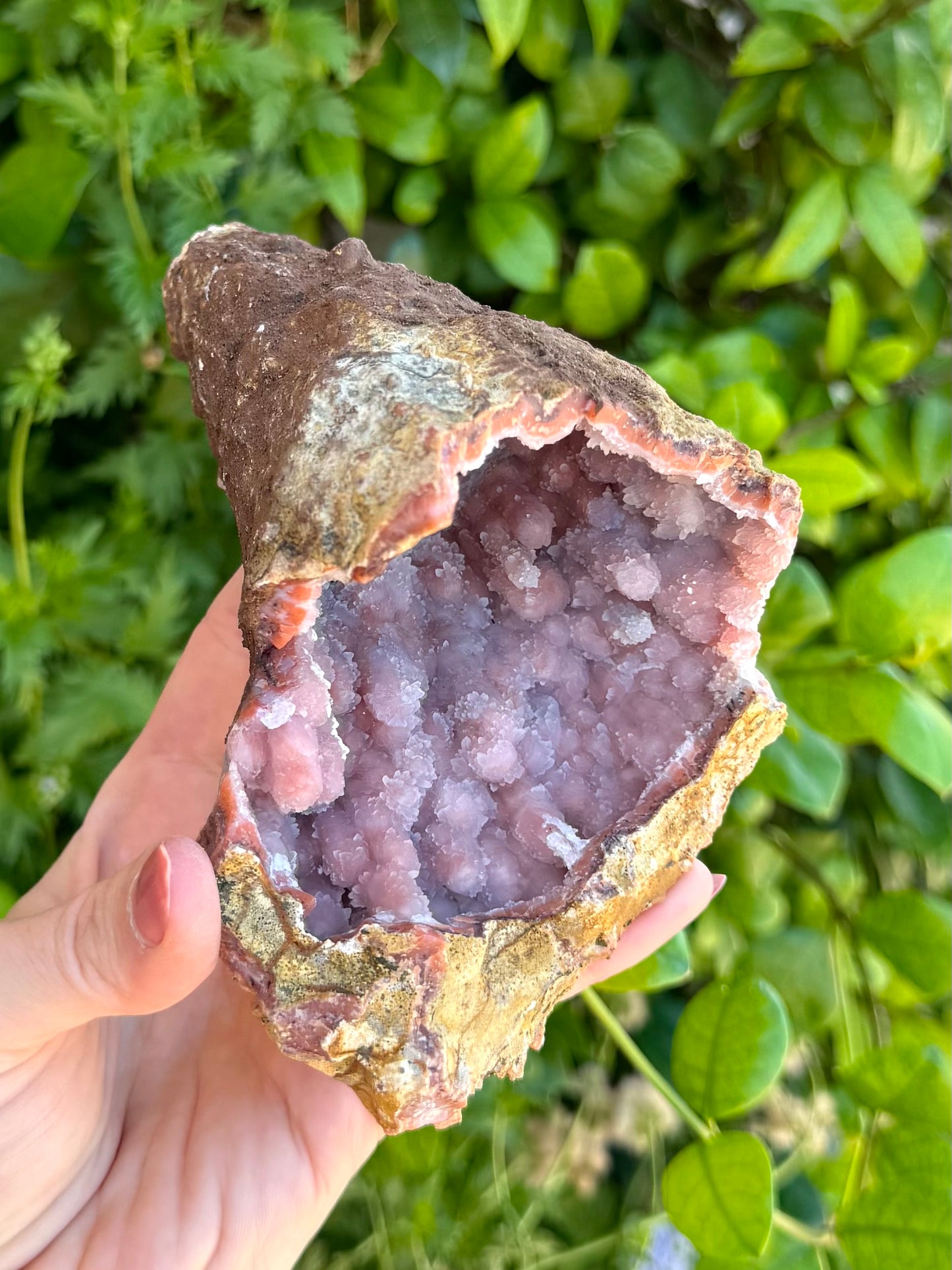 Looking into the geode, with the broad side covered with wide bumps instead of the usual spires. The piece is light colored, with an orange layer covered in milky white chalcedony and glittering small quartz crystals.