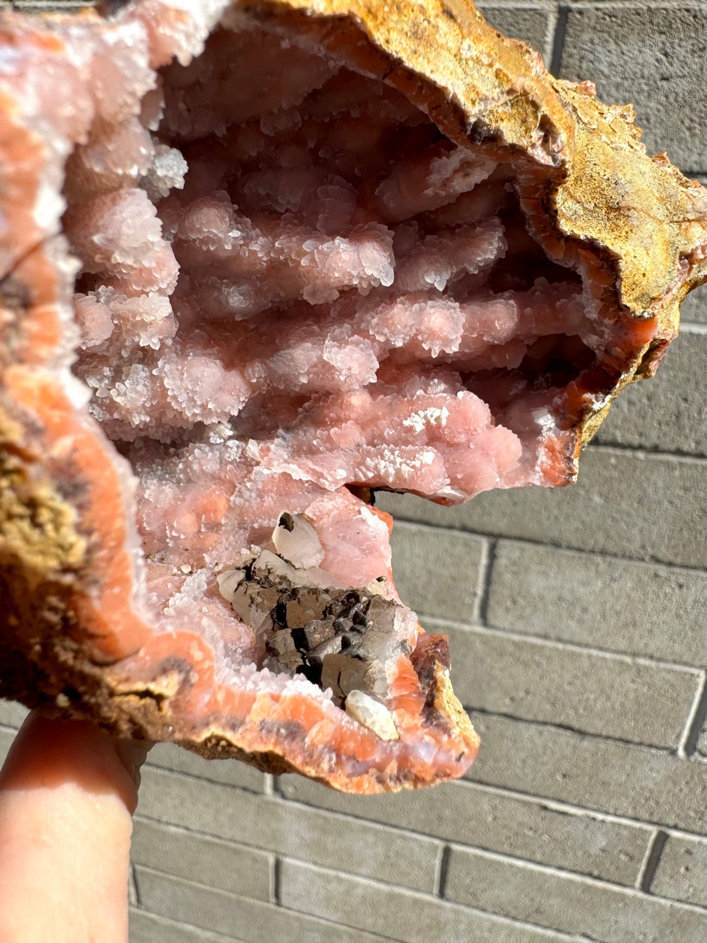 Detail of the cluster of minerals near the rim, calcite crystals partially covered with a dark brown mineral with metallic luster.