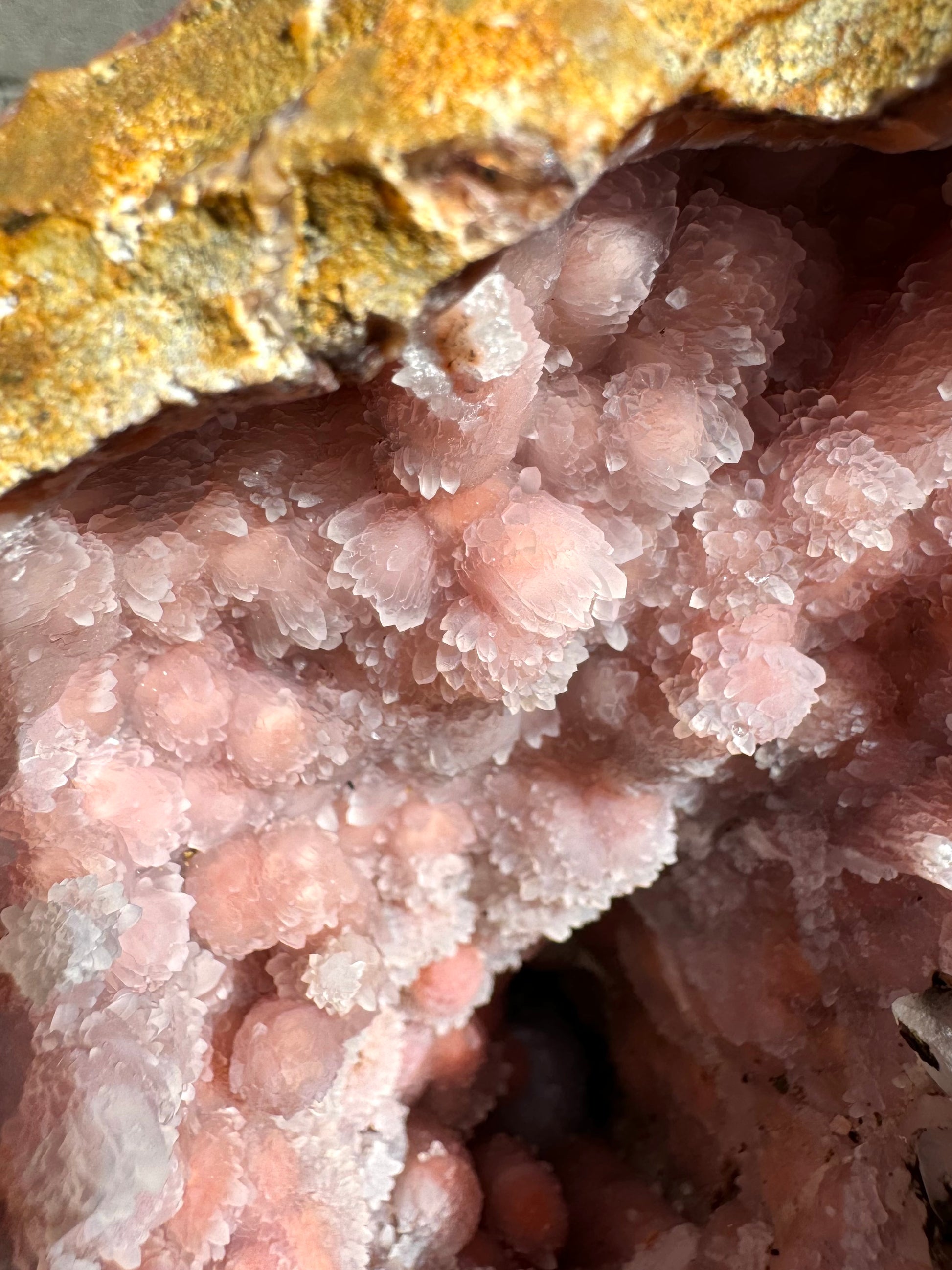 Detail of the milky white quartz growth, with orange faintly visible through. The crystals are shaped like parallel rice grains.