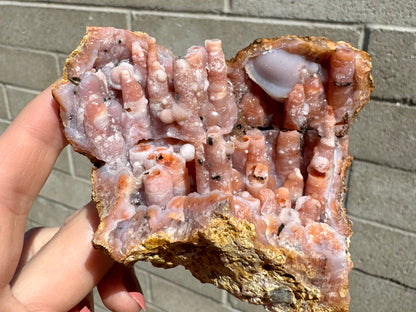 Full view of the geode piece in full sun, showing a crack horizontally through the center with brown mud-like material used to hide a repair. The white quartz surface glitters like snow.