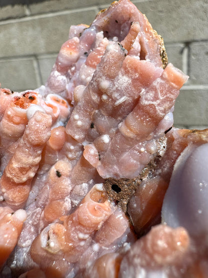 Detail of interesting agate patterns on the surface of the spires, forming white spheres and a honeycomb-like pattern. The repair is visible in the crack below the spires, which has white glue with bubbles visible in it, partially covered in a brown silty dirt.