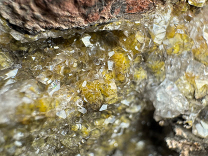Very close detail of colorless calcite crystals, the interiors a golden yellow from the wulfenite inside. The crystals are angular, with some in the center left giving some faint rainbows of iridescence.