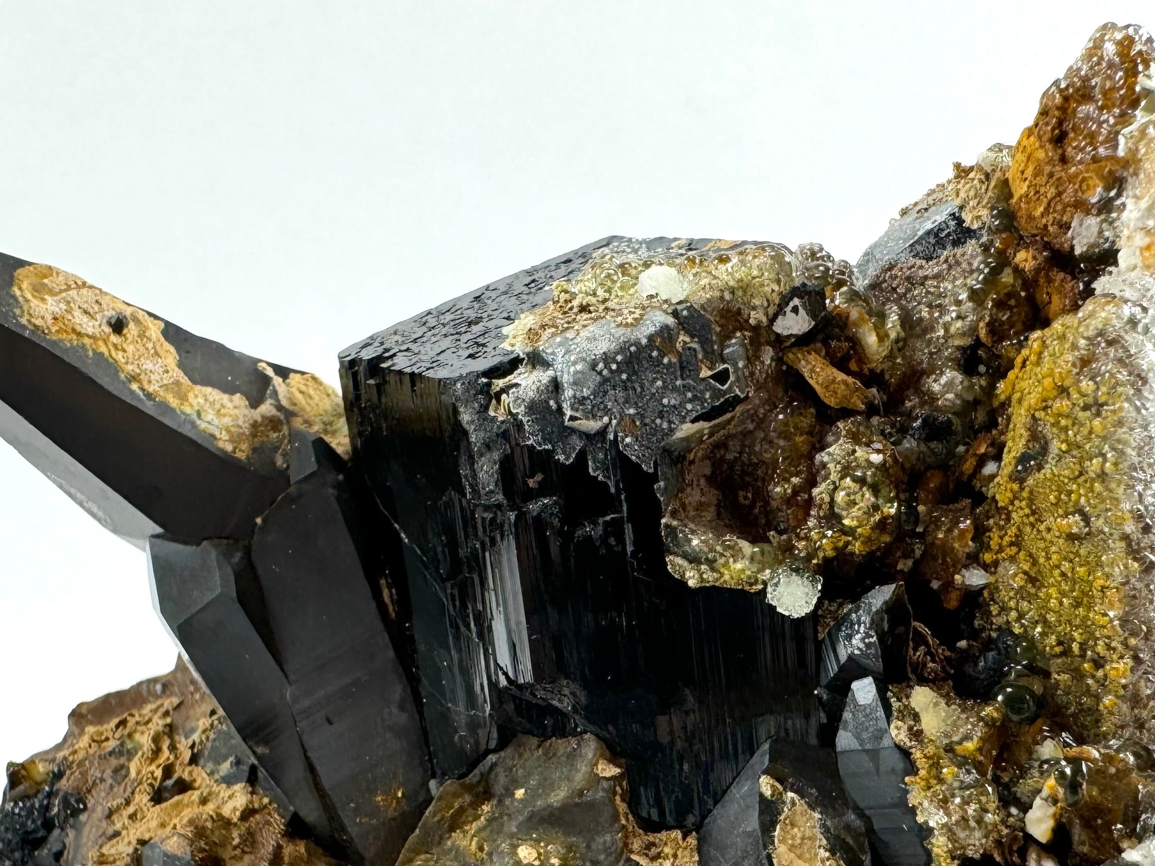 Detail of a black tourmaline with smoky quartz around it, partially coated with hyalite