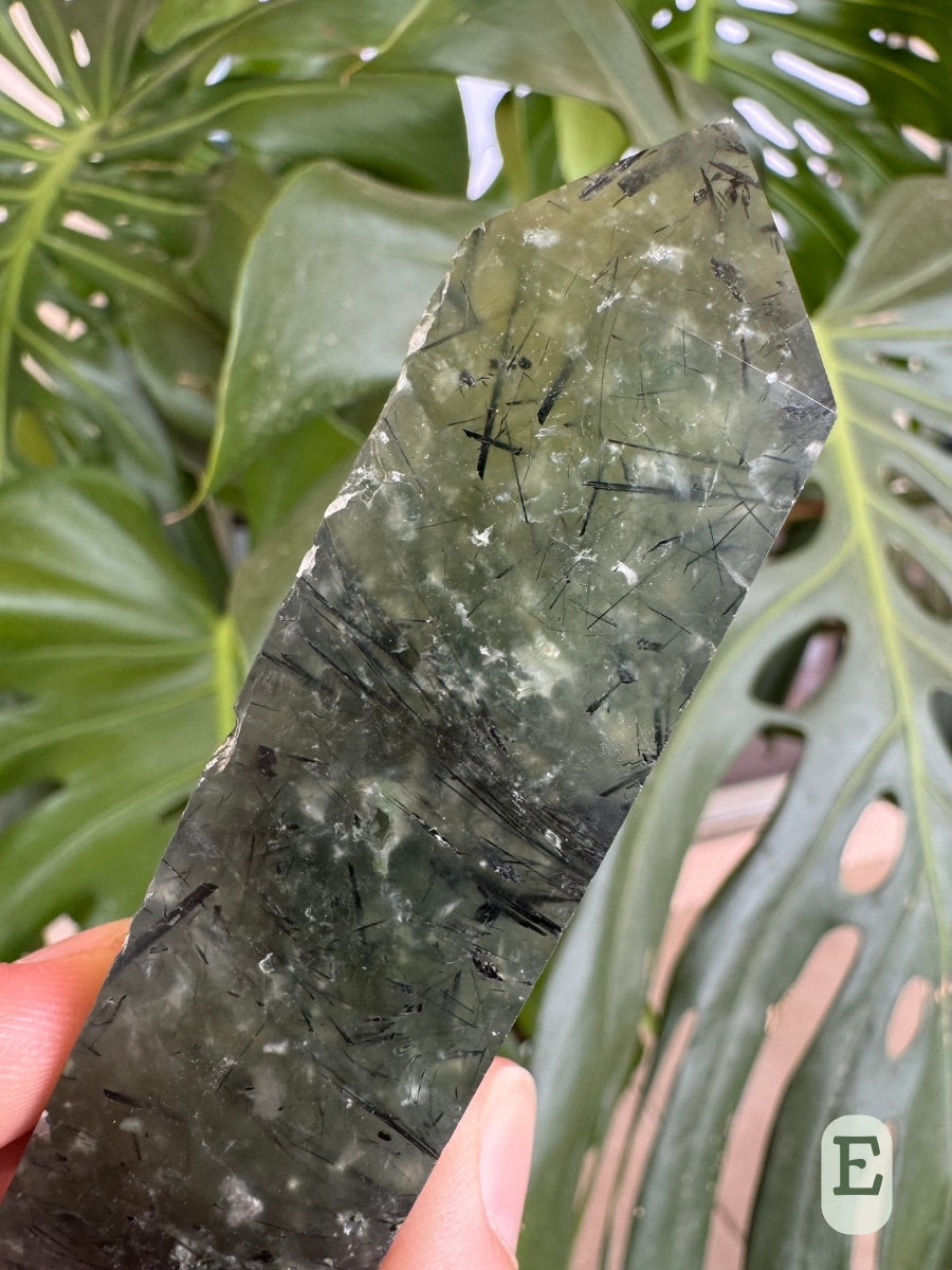 Option E, detail of the inclusions inside the translucent prehnite, large and fine needles of epidote and wispy white impurities. The point is lighter at the tip than the midsection.