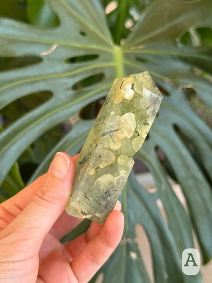 Option A, a four-sided tower carved from translucent light green botryoidal prehnite with open cavities winding through one side.