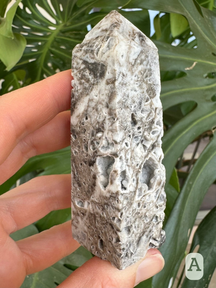 Option A, angled view of two sides of the piece, largely covered with the brown-gray patterning with several large druzy-lined holes