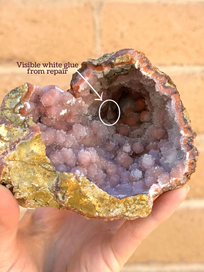 Looking down into the center of the geode, with a circle and arrow indicating a white patch near the tip with the caption "visible white glue from repair"