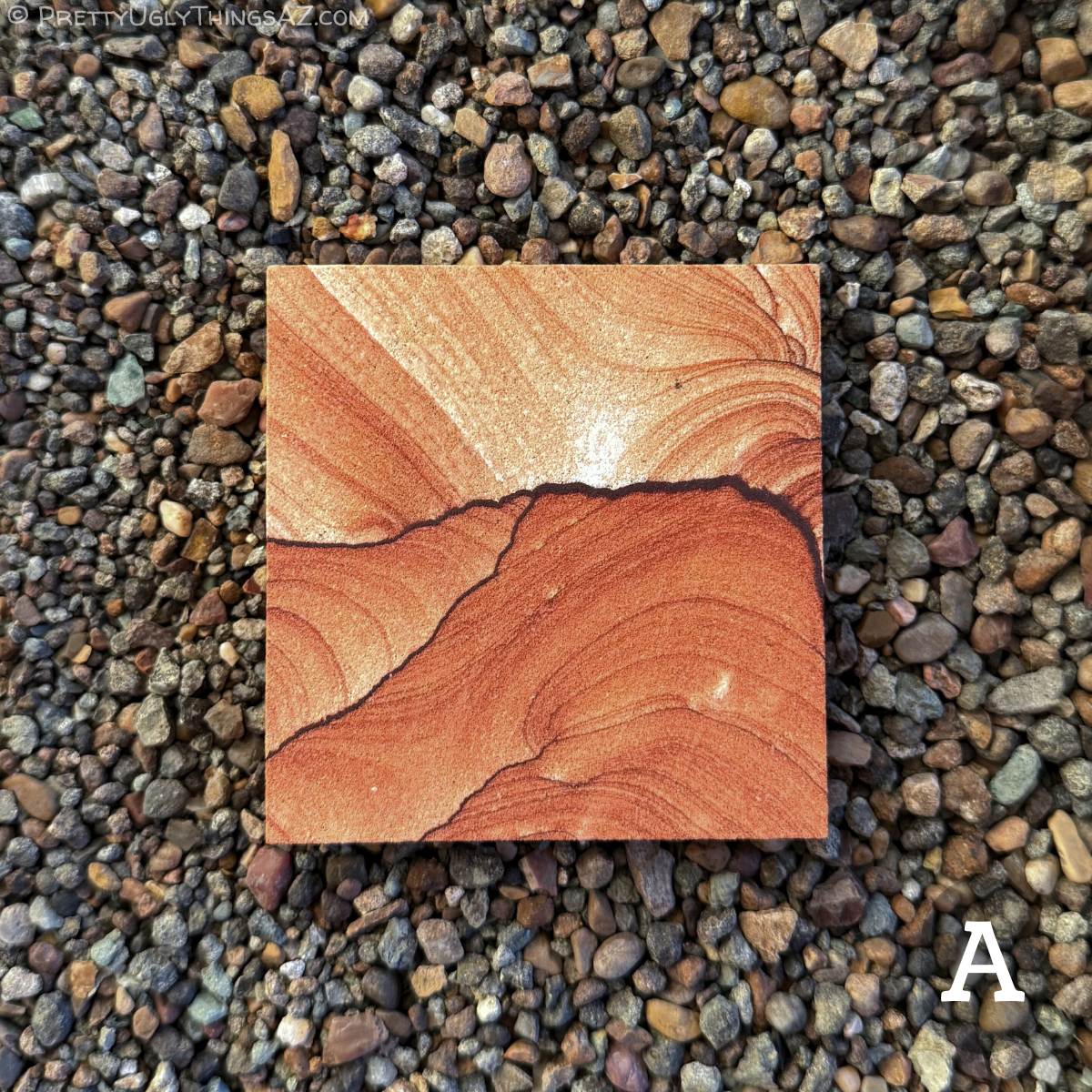 Option A, a near-square slab of sandstone with swirling curves of layers. Thin dark iron bands cut across the middle, the sandstone below a saturated red color with light curving layering. Above, the sandstone is lighter with sweeping layering reminiscent of a sky over hills.