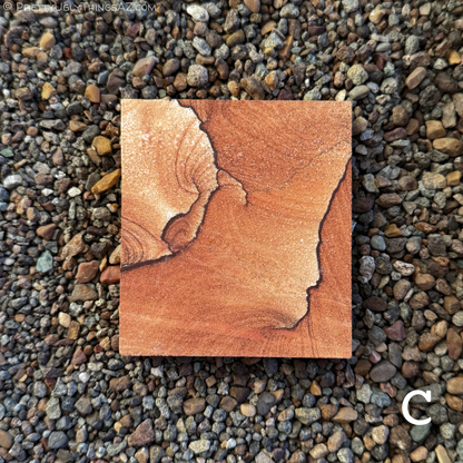 Option C, a near-square rectangular piece of sandstone with thin dark iron bands in a spiral-like formation, with faint curved layering fanning off them in a saturated orang-red sandstone. There is a patch of near-white sandstone with thin layering inside a ring of iron banding in the upper left corner.