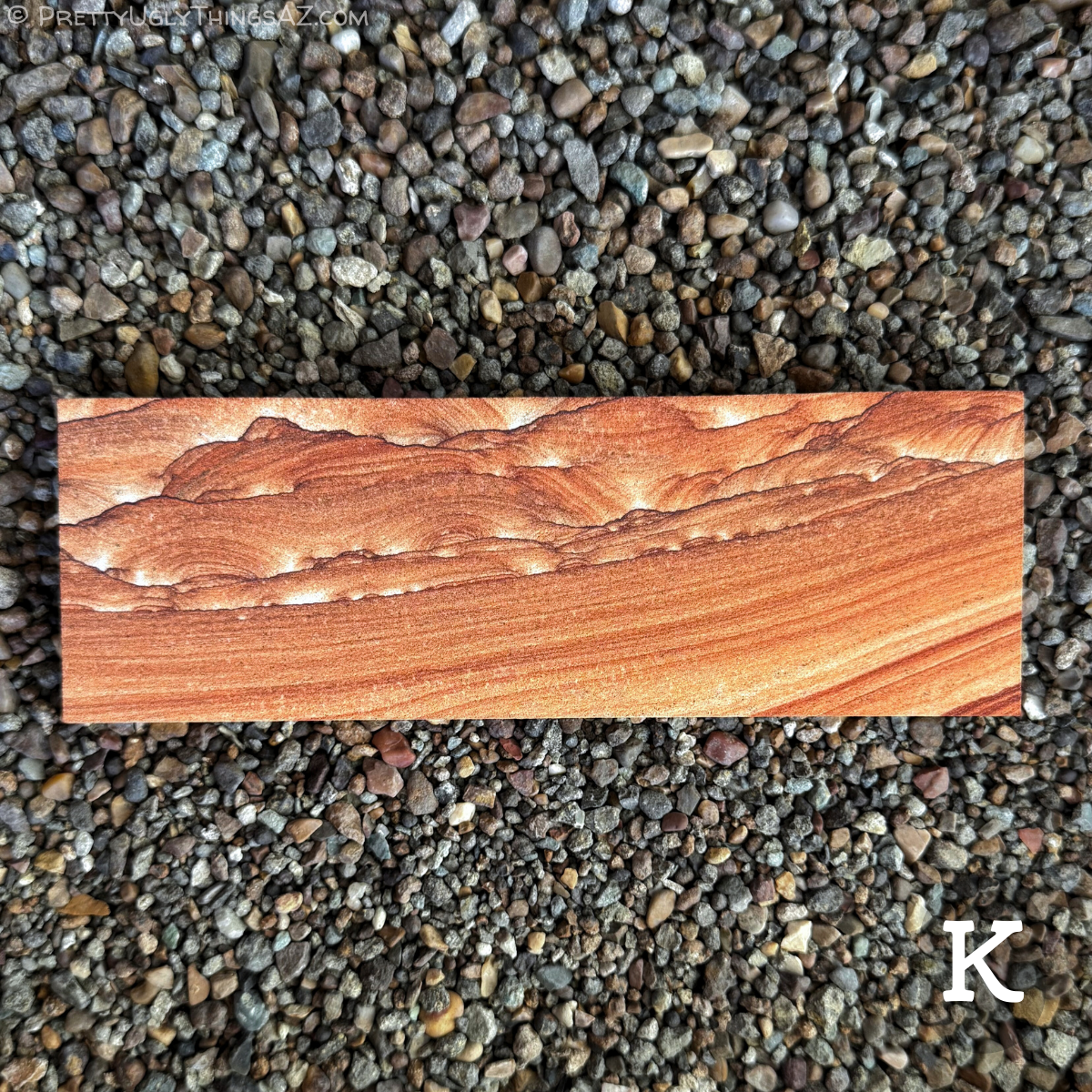 Option K, a long panoramic rectangular piece with good orange-red color saturation. The pattern is split in half diagonally across the piece, so the bottom right corner has broad parallel layering across it, while the upper left side has complex scallop patterning edged with thin dark iron bands, like mountains in the background.