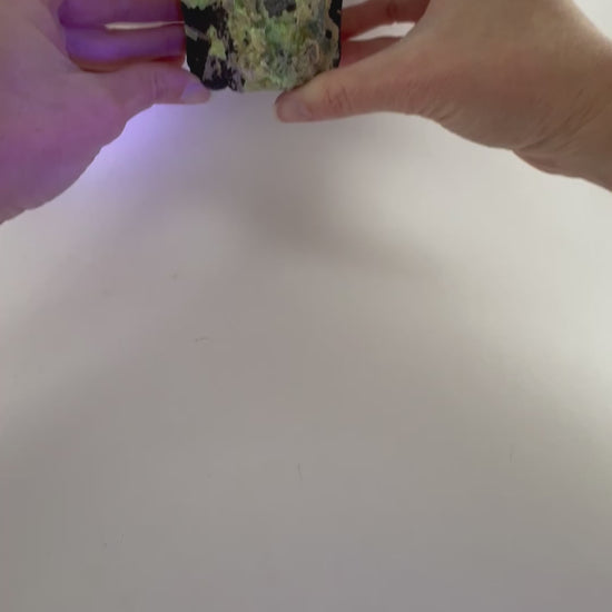 Short clip bringing the specimen into fluorescent light, showing the hyalite glow bright green with light blue undertones, and with purple light reflecting off the piece.