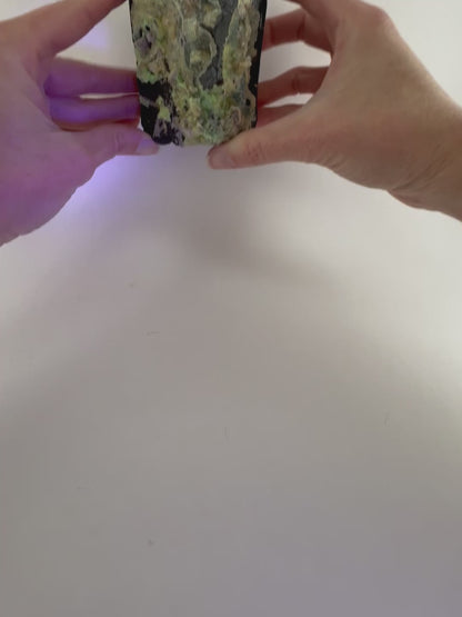 Short clip bringing the specimen into fluorescent light, showing the hyalite glow bright green with light blue undertones, and with purple light reflecting off the piece.