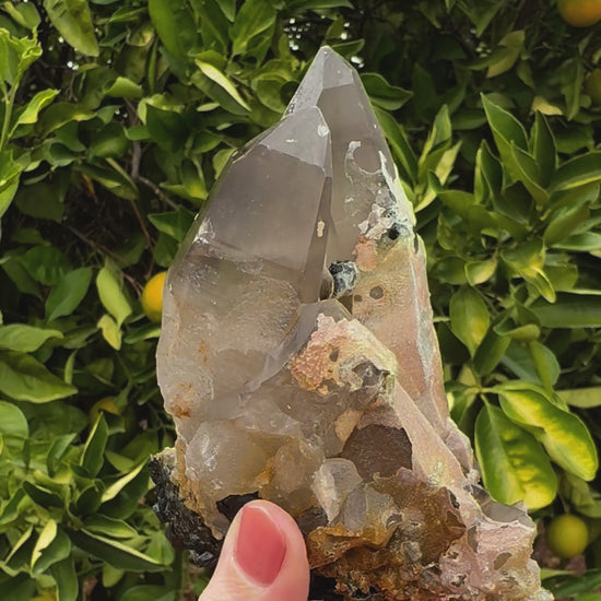 Short clip of the specimen being rotated and tilted to show crystals at different angles. The smoky quartz has good clarity, with a satiny surface. The hyalite has a slight green-yellow daylight fluorescence.